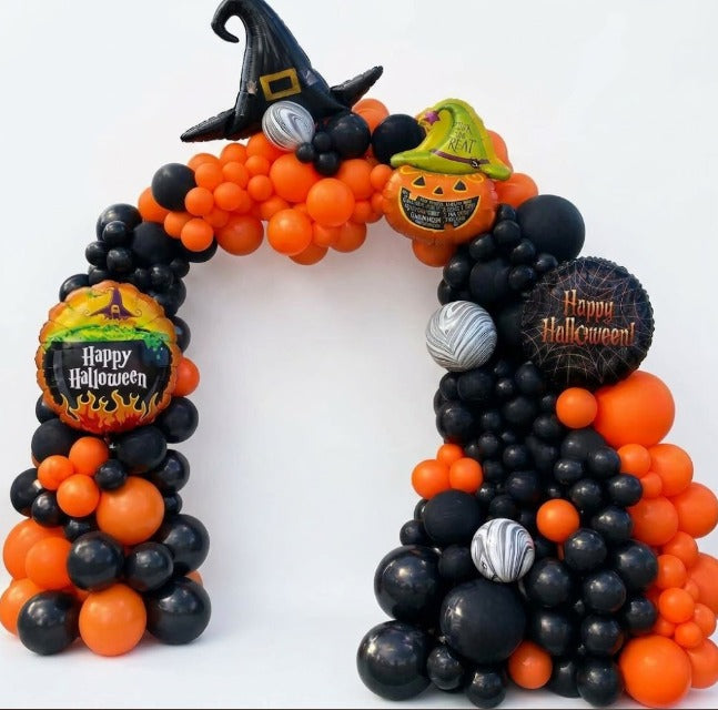 Organic Halloween balloon arch in orange and black with a witch hat balloon, a pumpkin balloon and Happy Halloween foil balloons