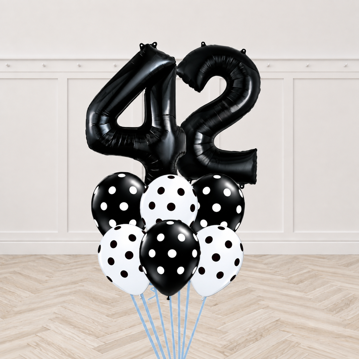 Two black number foil balloons forming a two-digit age with six mixed black and white polka-dot latex balloons