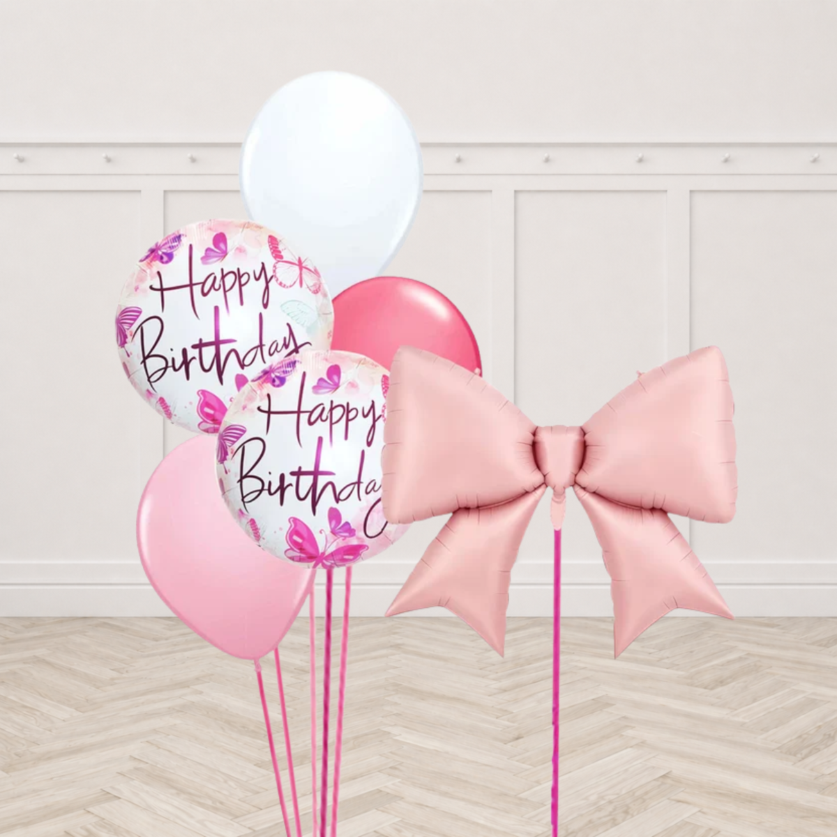 Blush pink bow shaped foil balloon with two white round foil balloons printed Happy Birthday with pink and purple butterflies and white dark pink and light pink latex balloons on pink ribbons