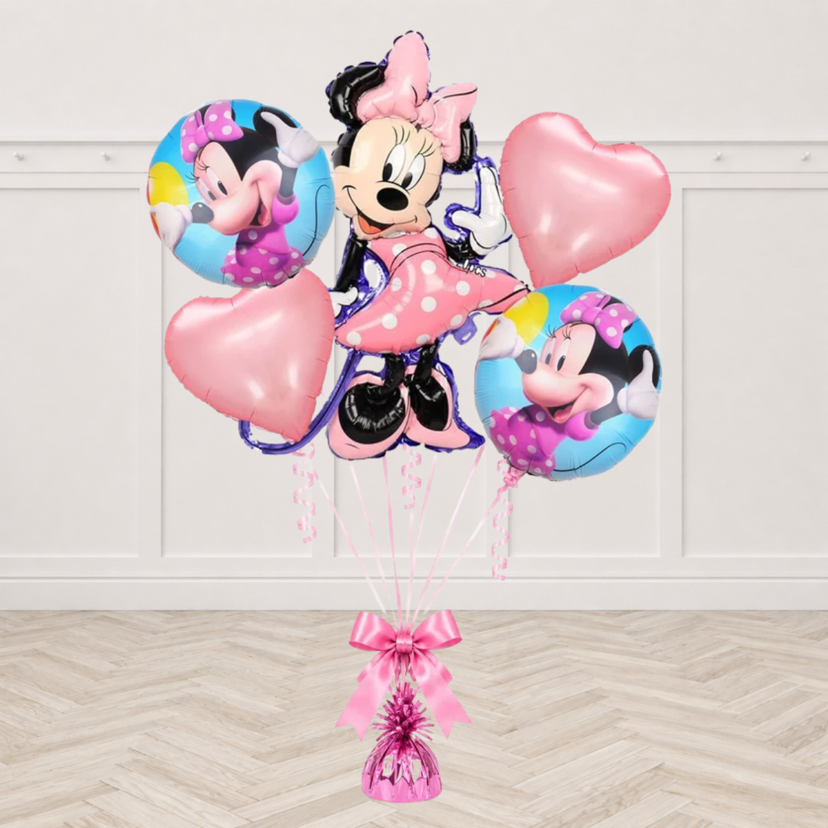 Minnie Mouse shaped foil balloon with two blue round Minnie Mouse foil balloons and two pink heart foils tied to a pink balloon weight with a pink bow