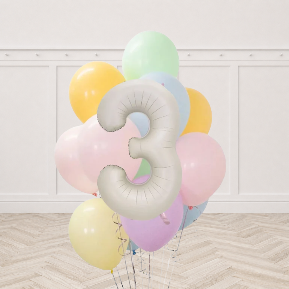 Cream number 3 foil balloon in front of a bunch of pastel mint green peach yellow light blue pink and lilac latex balloons with silver ribbons