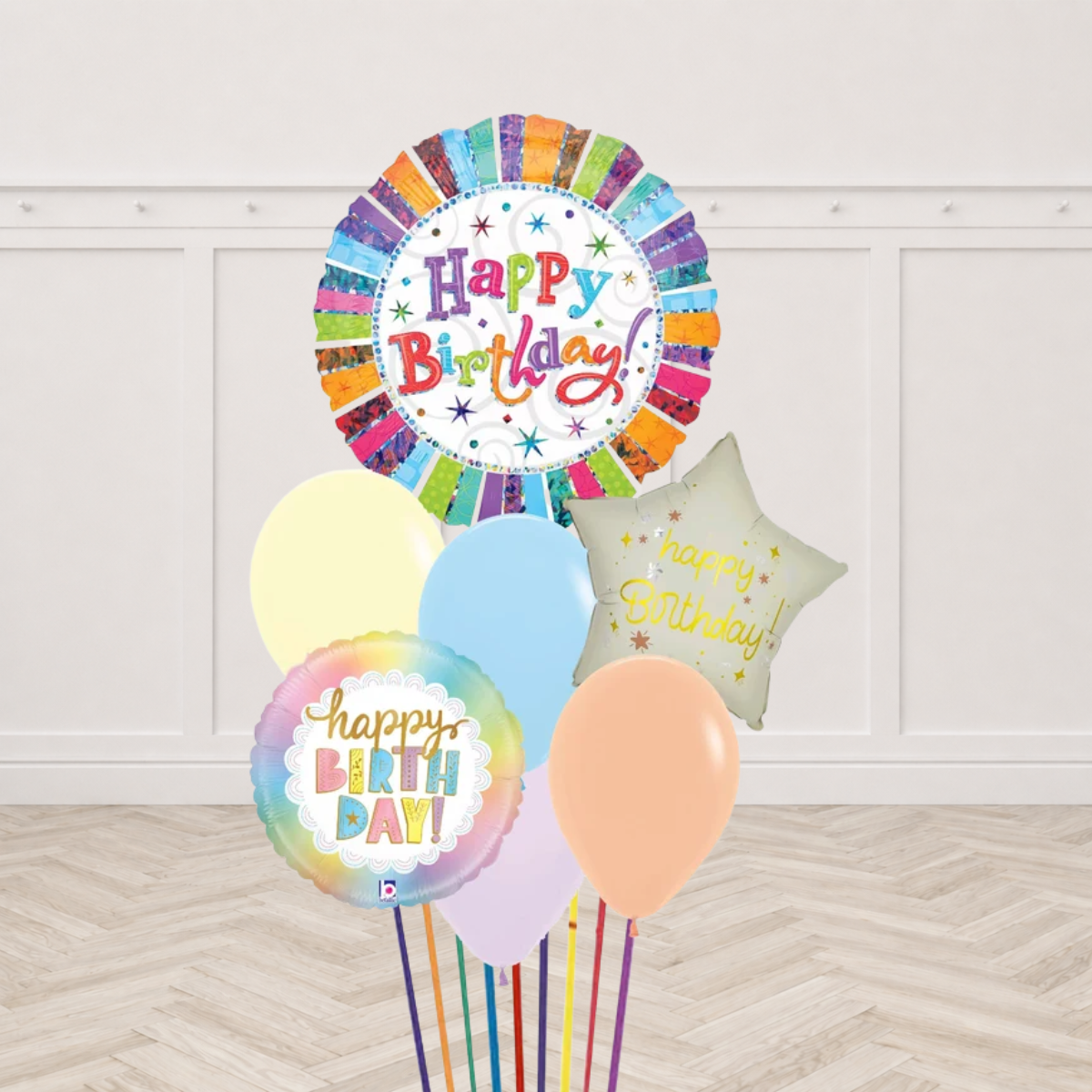 Large round rainbow Happy Birthday foil balloon, a pastel rainbow round Happy Birthday foil and a cream star Happy Birthday foil with pastel yellow light blue lilac and peach latex balloons on multicolor ribbons