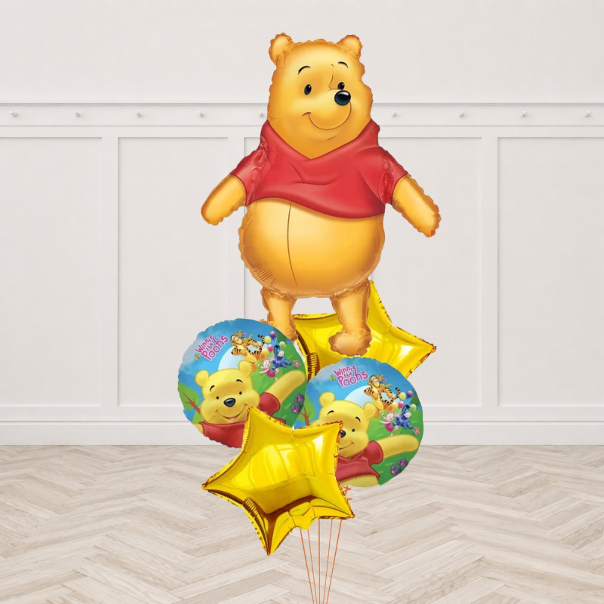 Winnie the Pooh shaped foil balloon with two round Winnie the Pooh foil balloons showing Pooh Tigger Piglet and Eeyore and two gold star foils on orange ribbons